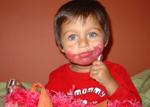 baby boy applying lipstick to face